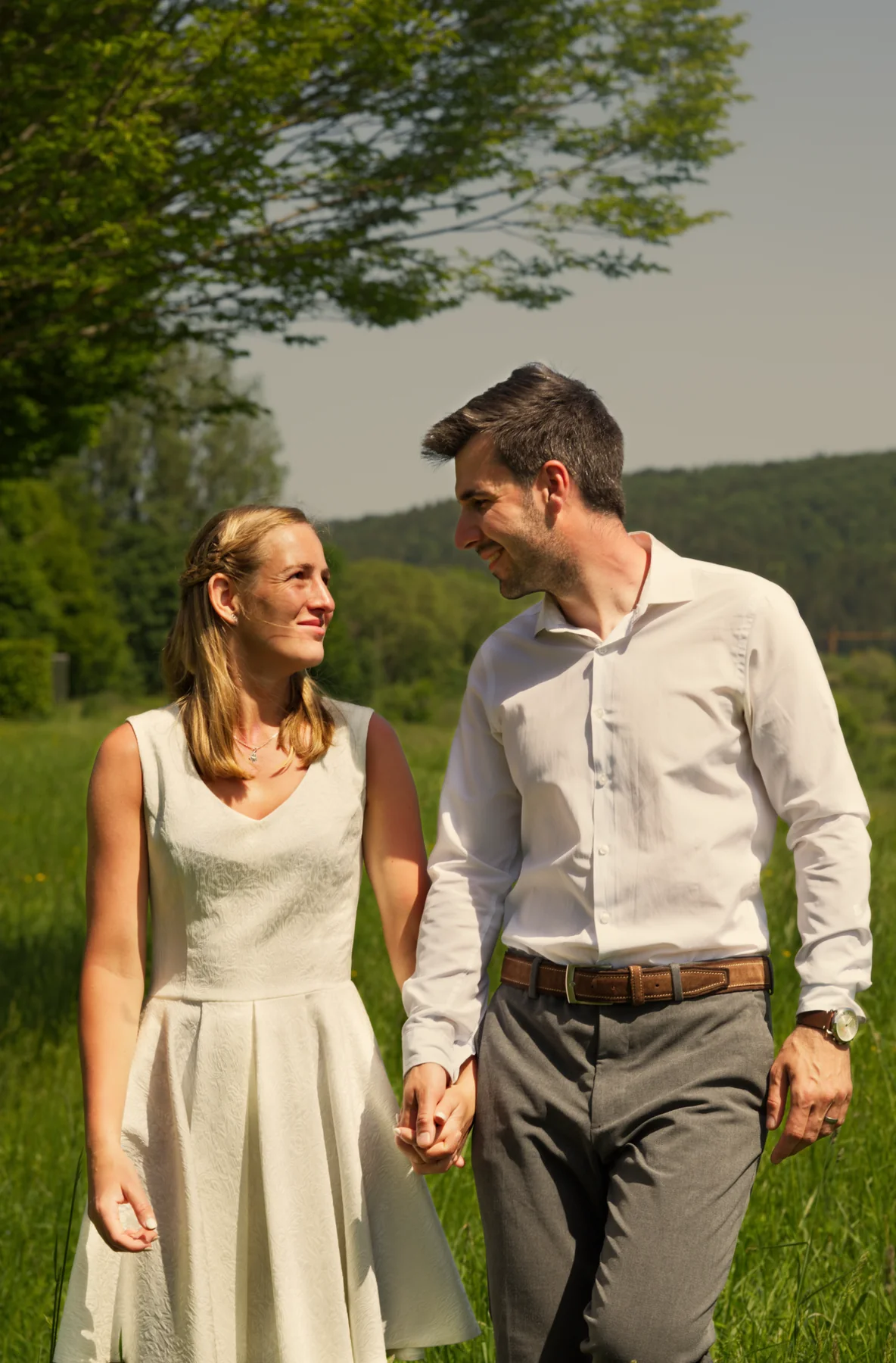 Scarlett und David gehen Hand in Hand über eine Wiese